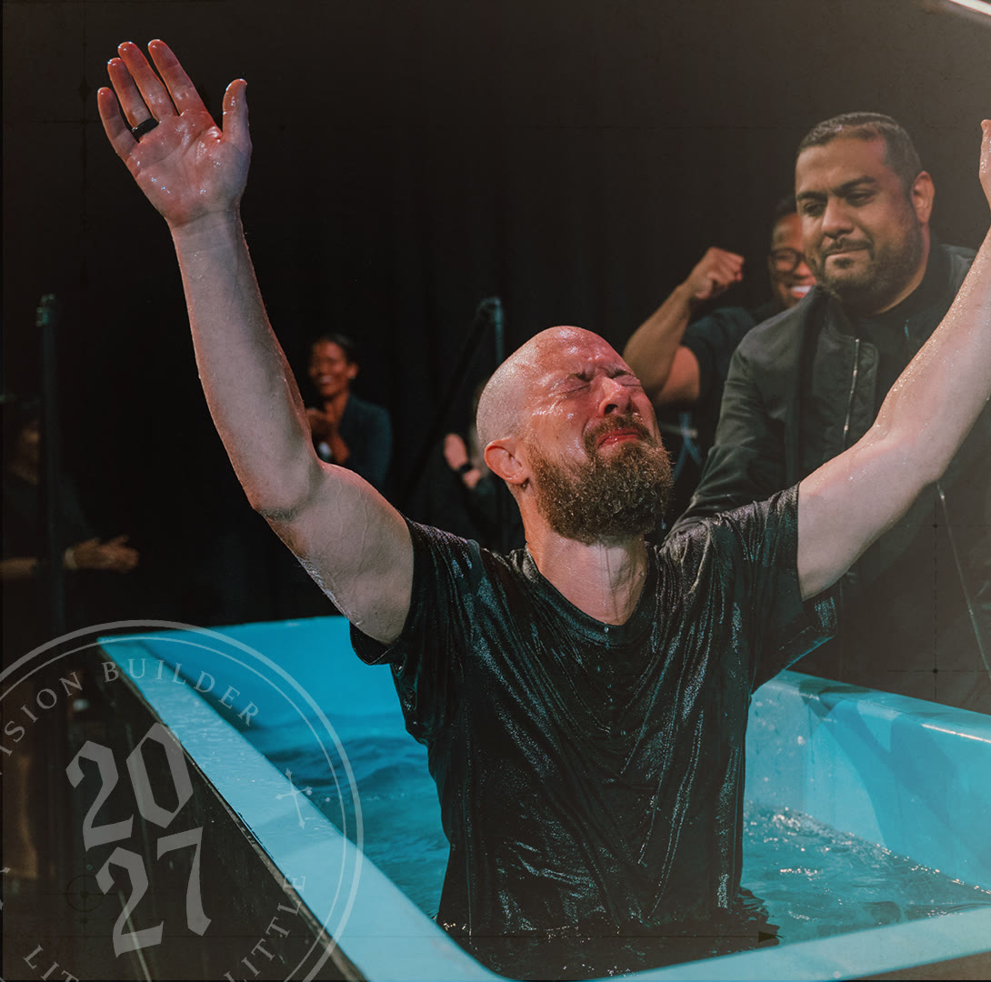 A man being baptized with his hands raised