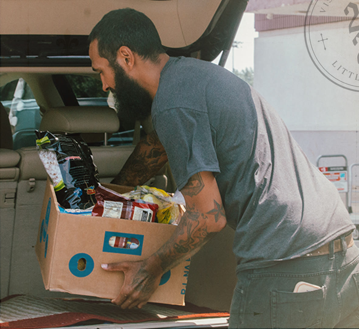 A man loading a box of groceries into a car