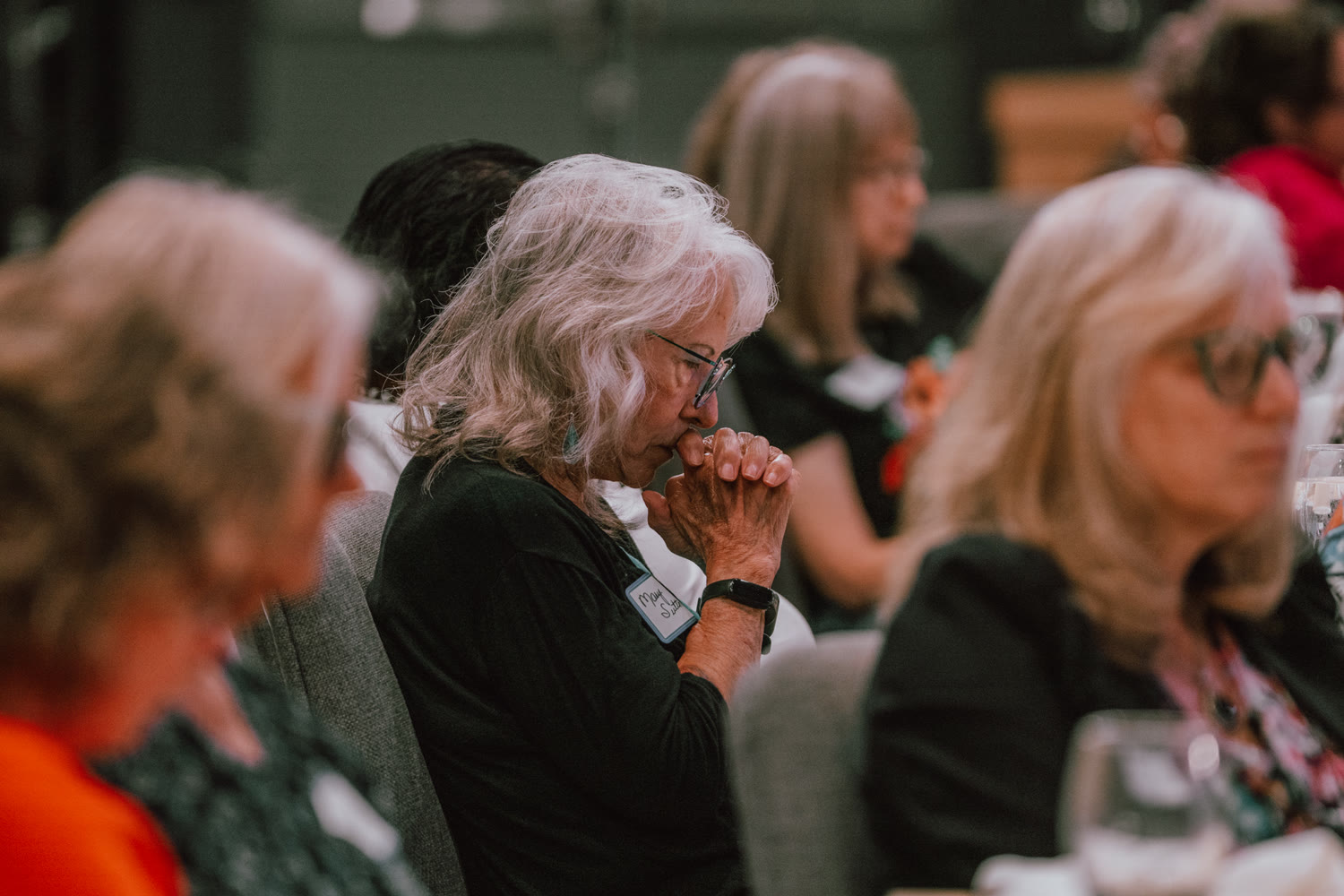 A woman praying at a Wisdom Club gathering